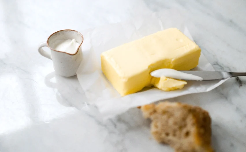 Un bloque de mantequilla fresca junto a una jarra de crema